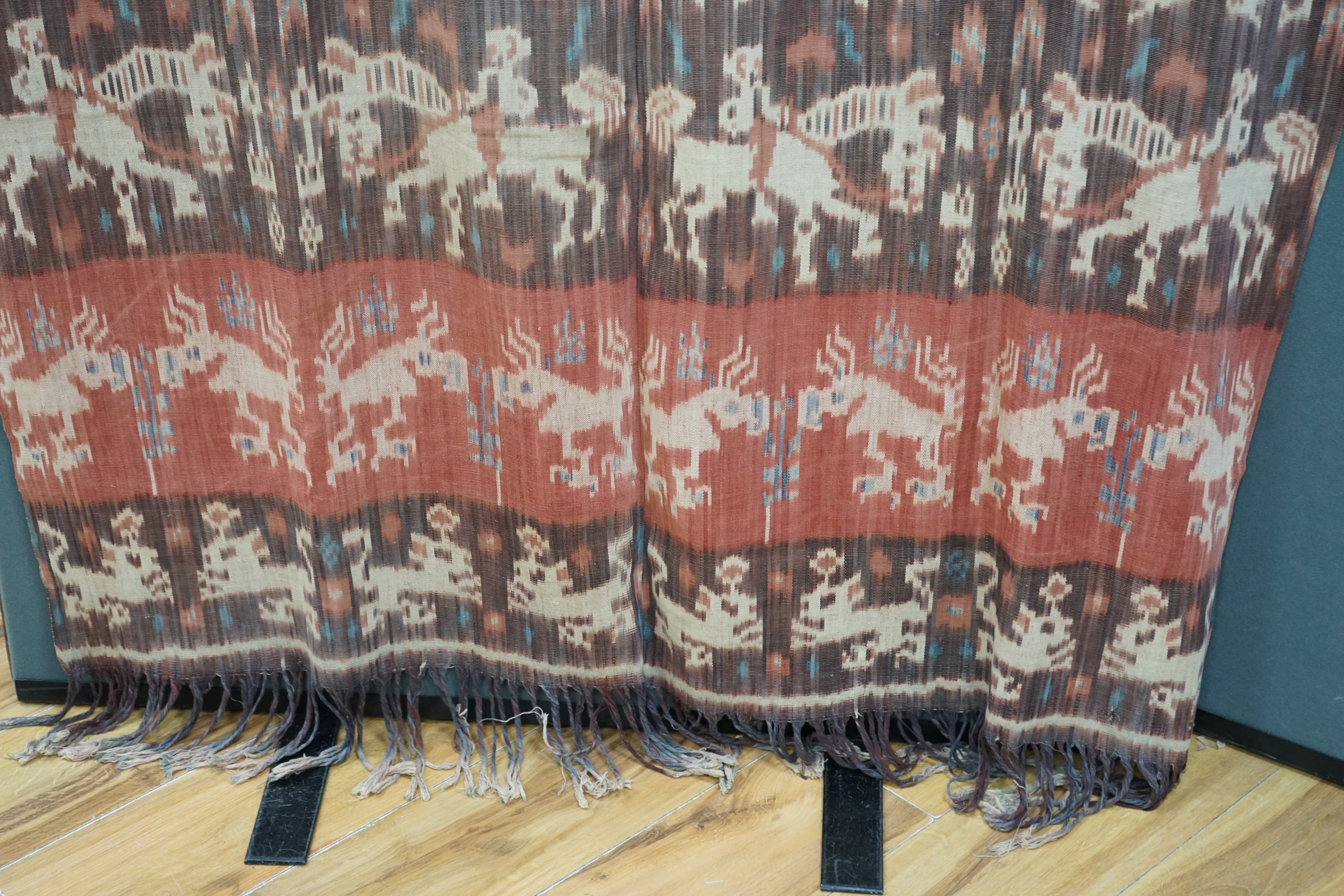 A hand woven hand dyed Ikat Sumbanese Hinggi (shoulder cloth), together with an Indian chain stitch embroidered panel, the Hinggi woven on two short 56cm wide looms sewn together forming horizontal bands, depicting men o